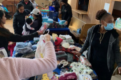 Women gathered around a table selecting baby clothes.