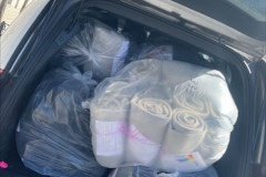 The trunk of a van filled with bags of gray blankets.