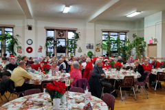 Members of the Catholic Charities Pete McGuiness Older Adult Center are seated enjoying a delicious Christmas feast.