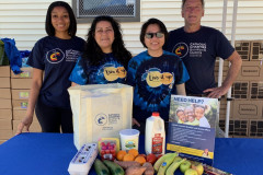 Staff from Catholic Charities Brooklyn and Queens Community Outreach Services standing next to a table full fresh produce.