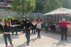 A group of older adults practicing Tai Chi outdoors.