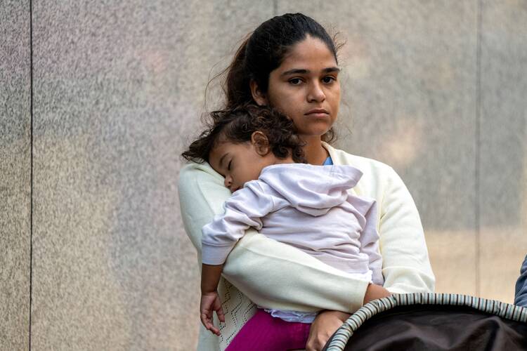Migrant woman carrying sleeping daughter.