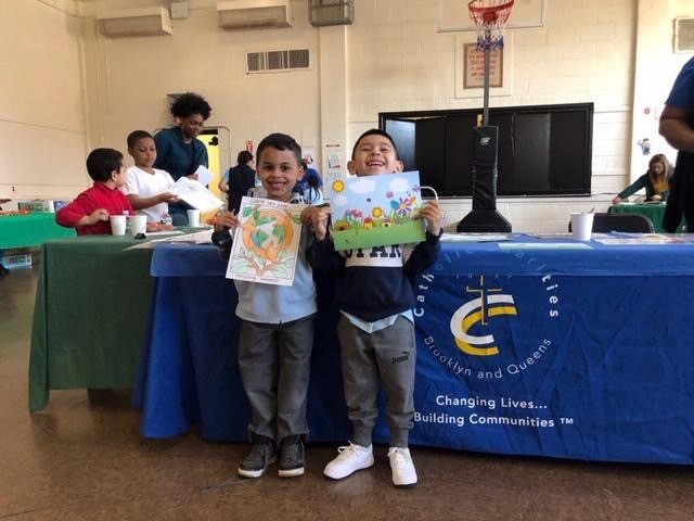 Two smiling children holding up their drawings.